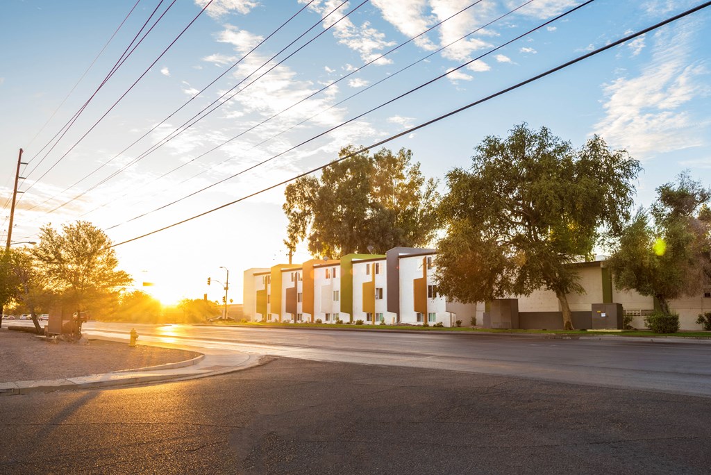 an empty street in front of a building with the sun setting