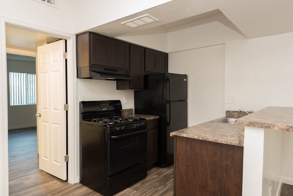 an empty kitchen with a black stove and refrigerator