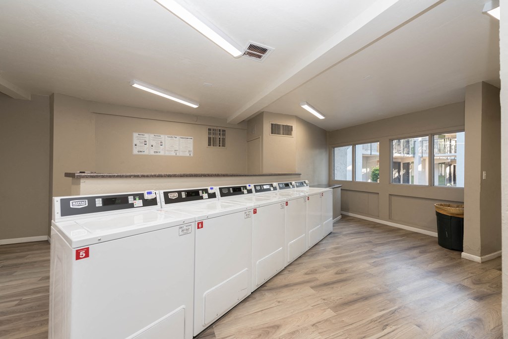 a row of washers and dryers in a room with a wood floor