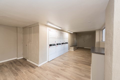 the living room and kitchen of an apartment with white appliances and wood floors