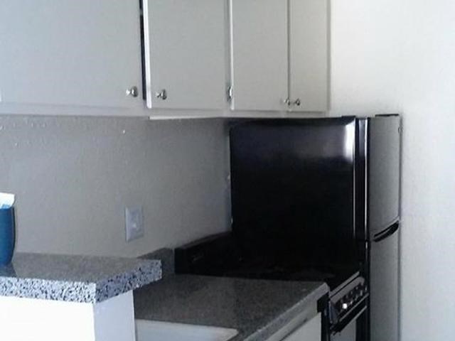 a kitchen with a black refrigerator and white cabinets
