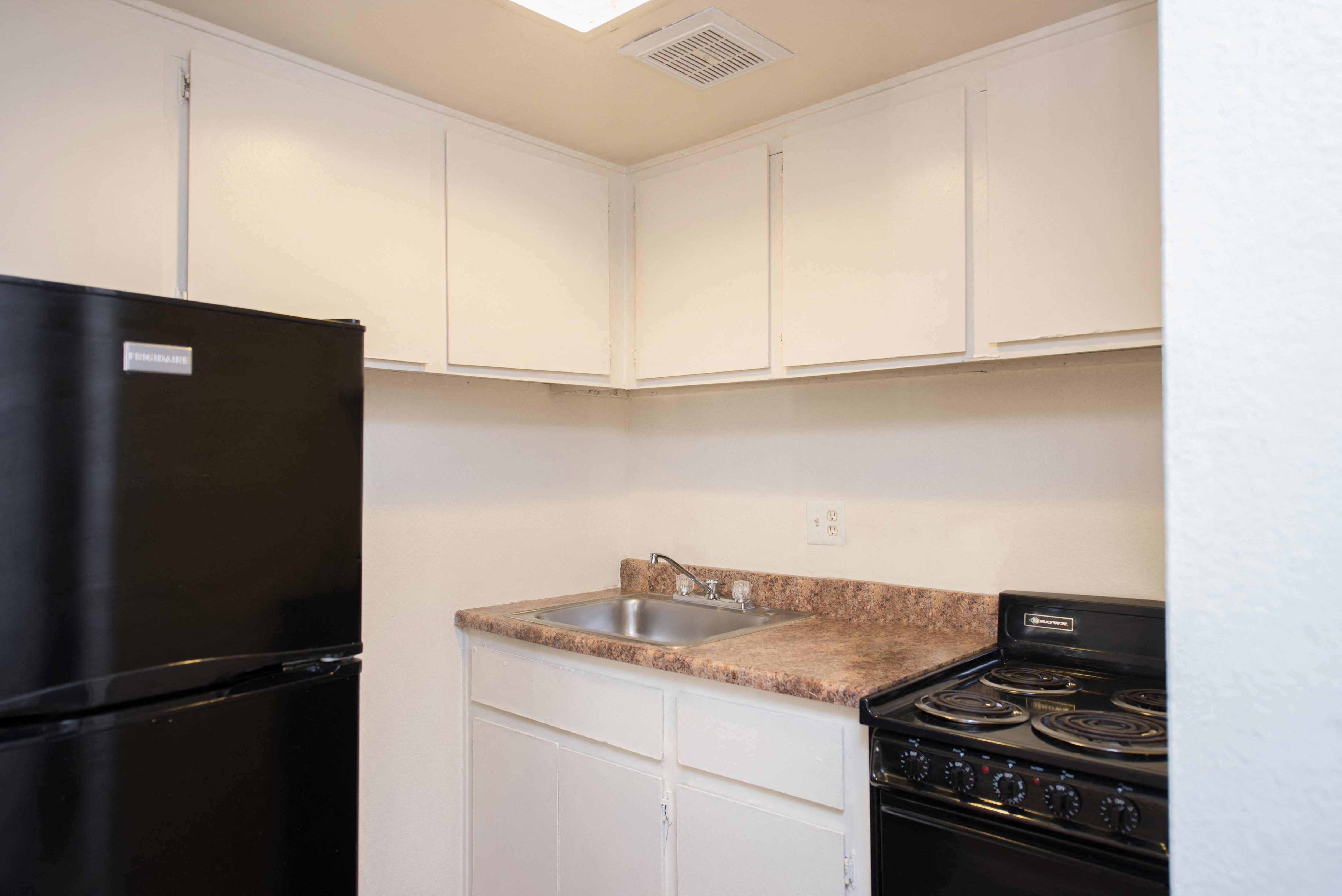 a kitchen with white cabinets and black appliances and a sink