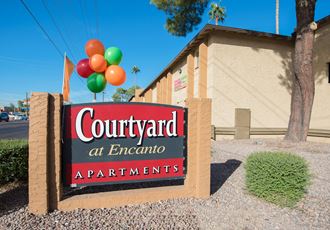 a sign for the courtyard apartments with balloons
