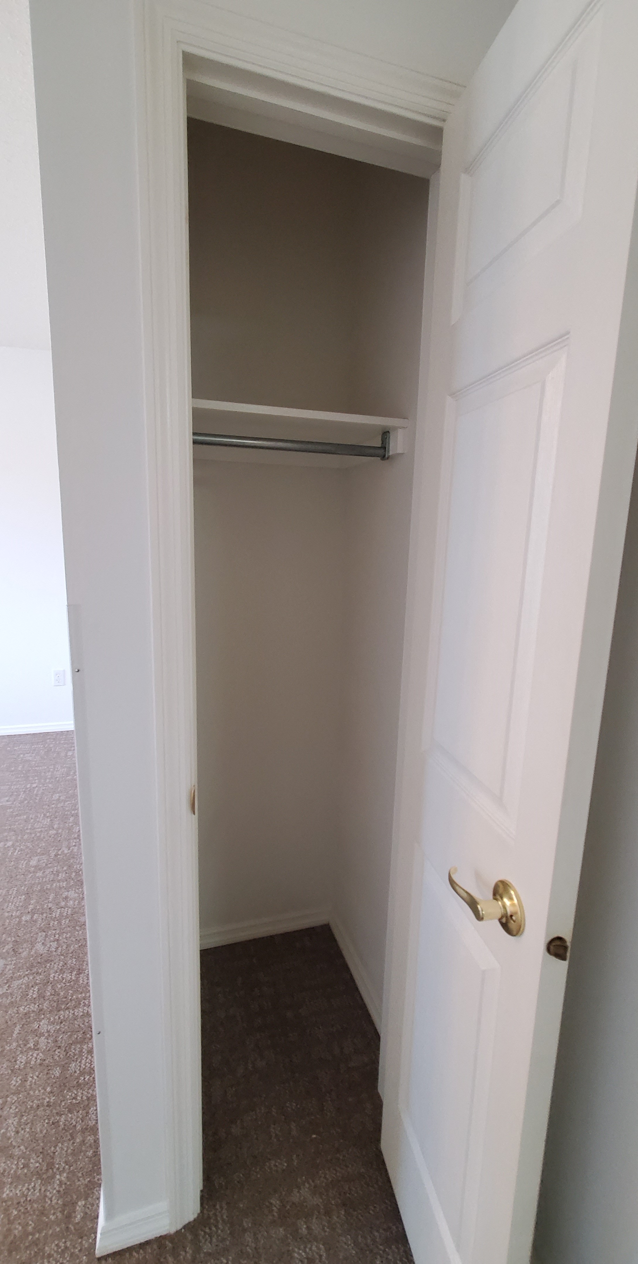 an empty closet with a white door and a white closet door