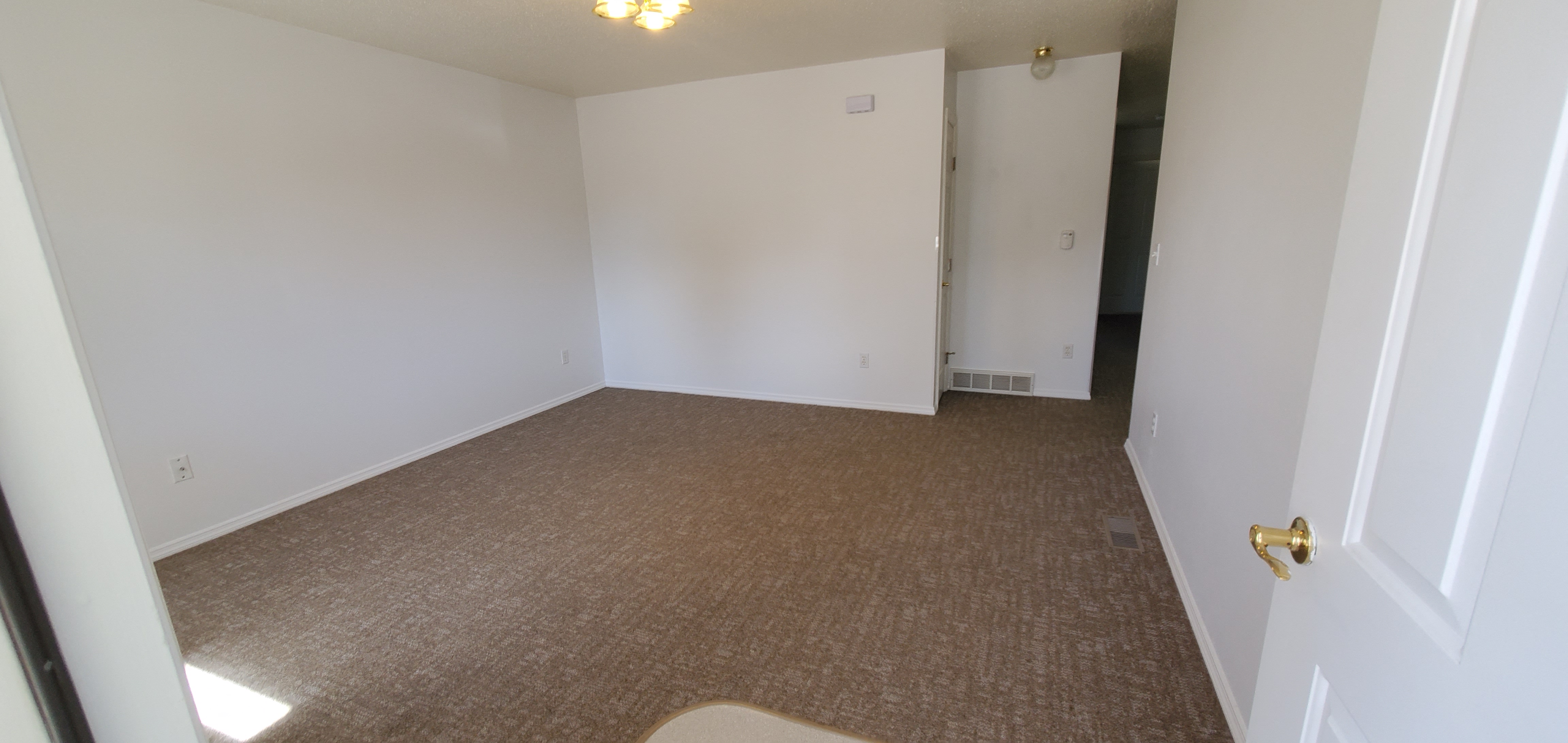 an empty room with a carpet and white walls