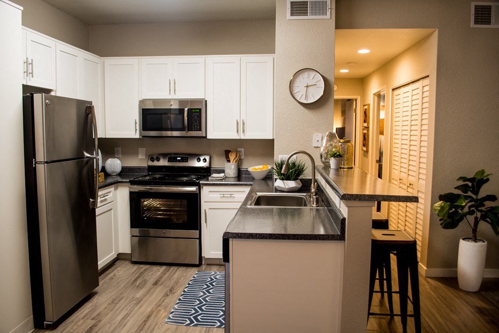 Sacramento California Apartments for Rent - Waterford Cove - Kitchen with Dark Countertops, White Cabinets, Small Breakfast Bar, and Appliances