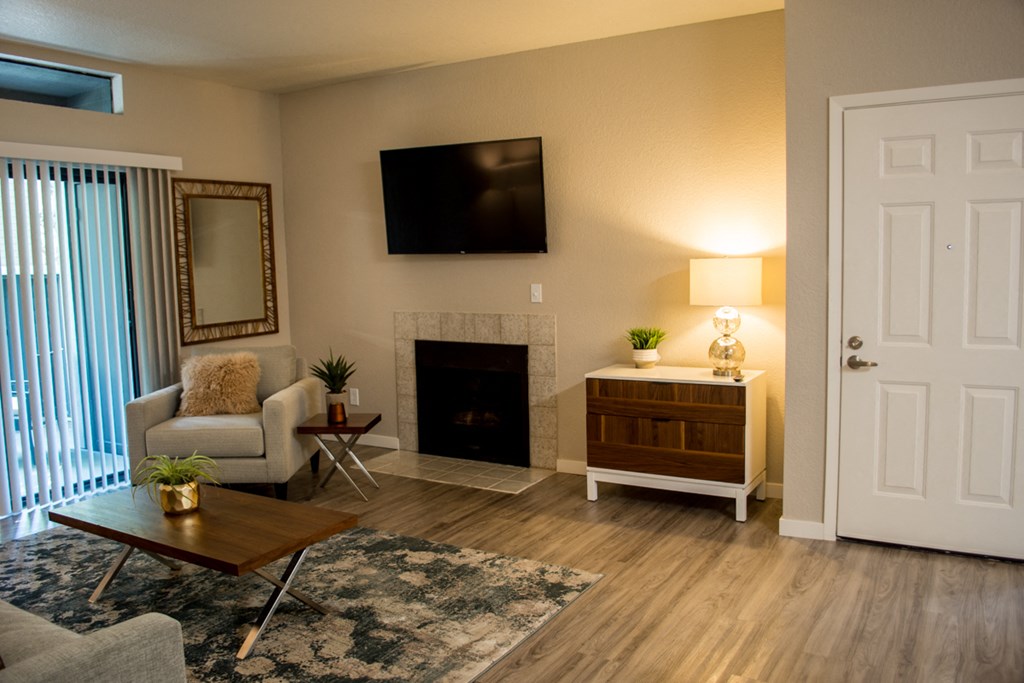 Sacramento Apartments - Waterford Cove - Living Area with Fireplace, Wood-Style Flooring, and Patio