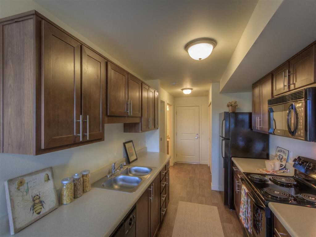 Apartments for Rent in Lynnwood, WA - Urban Center - Kitchen with Dual Sinks, Black Appliances, White Countertops, and Brown Cabinets