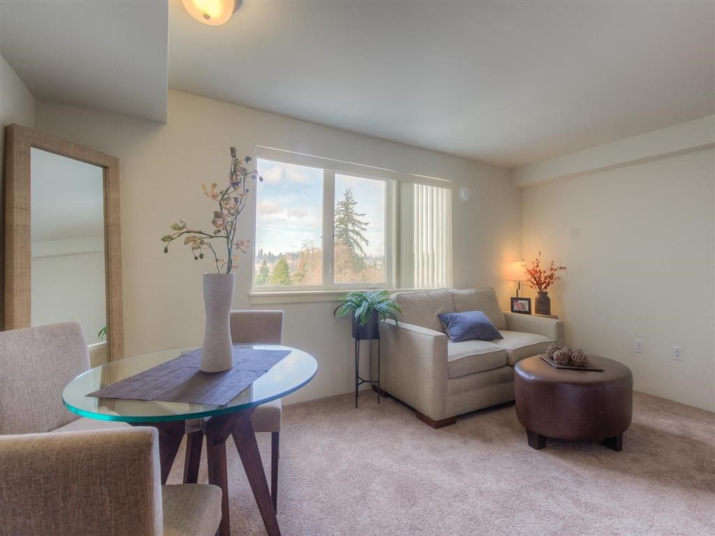 Apartments in Lynnwood, WA - Urban Center - Living Room with Loveseat, Ottoman, Lamp, and Window