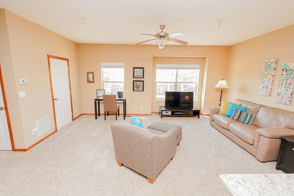 a living room with a couch and a chair and a ceiling fan