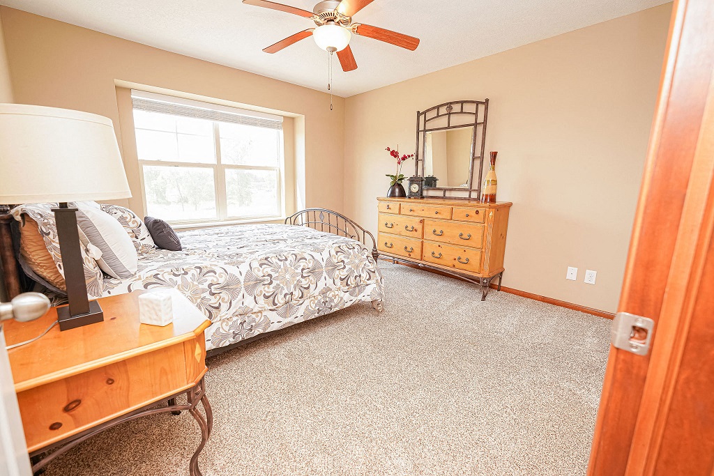 a bedroom with a bed and a dresser and a ceiling fan