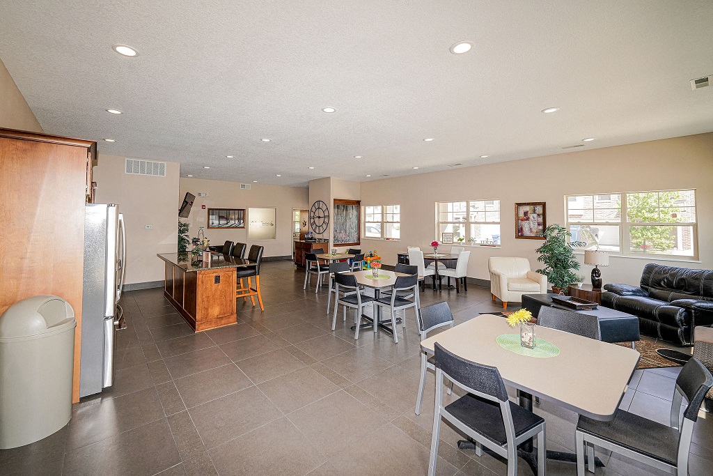 a dining room and living room with tables and chairs and a refrigerator