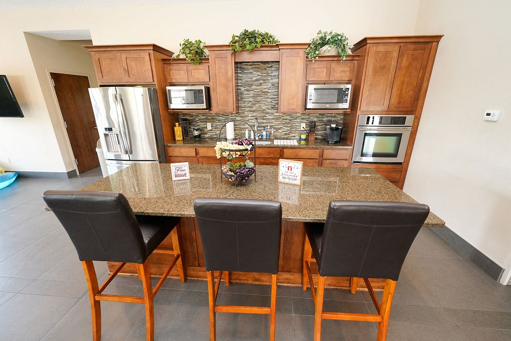 a kitchen with a counter top with three chairs
