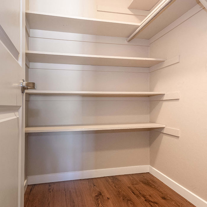 Apartments in Walnut Creek CA - The Meridian - Bedroom Closet with White Shelves and Hangar Rack, and Wood Style Flooring