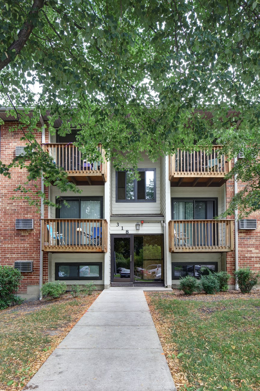the outlook of an apartment building with a sidewalk and trees