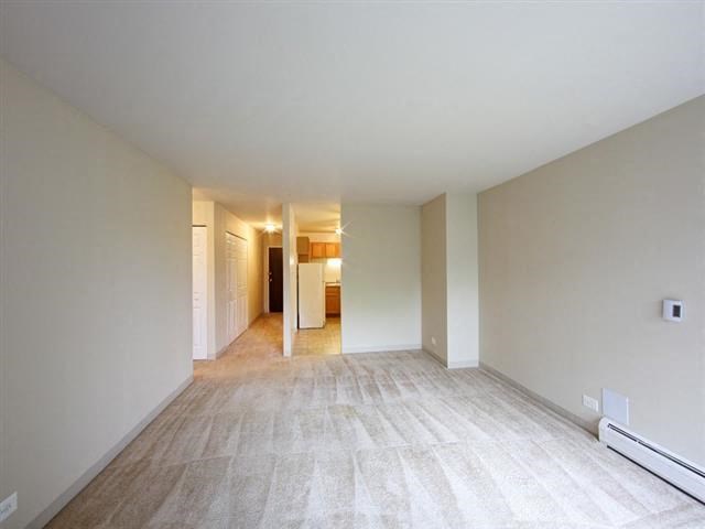 an empty living room with white walls and a wood floor