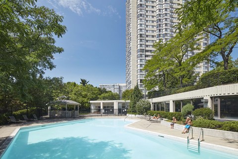 a swimming pool in front of a building with people in it