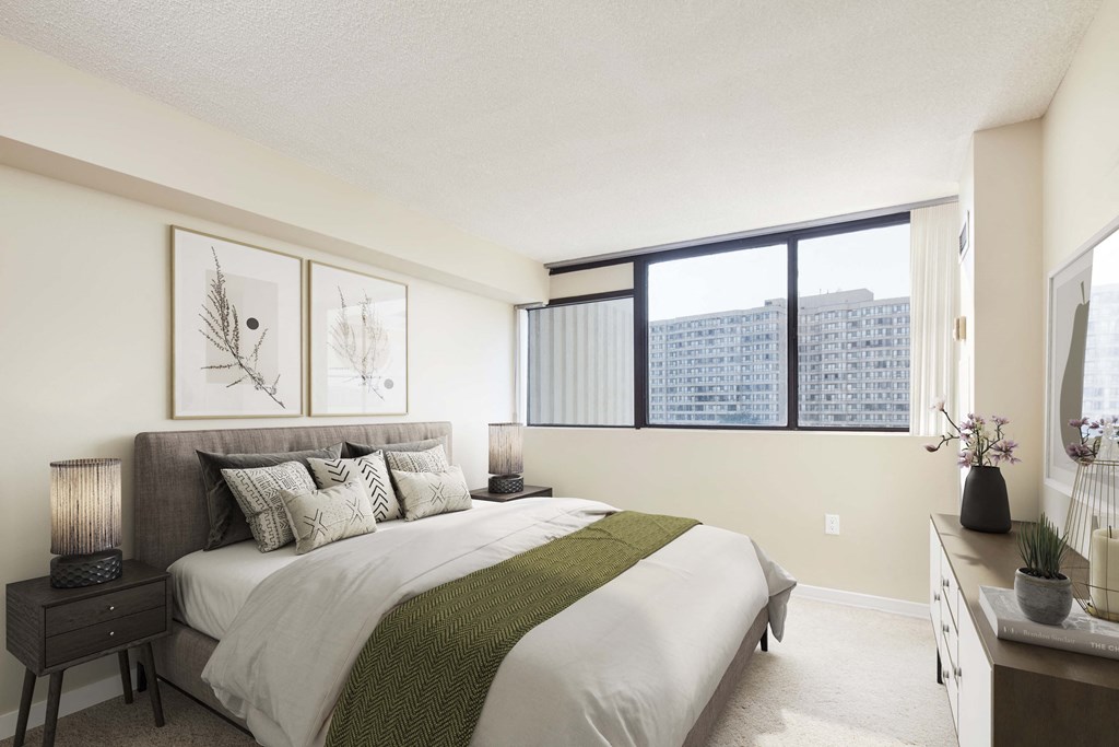 bedroom with large windows and a bed with white sheets and pillows