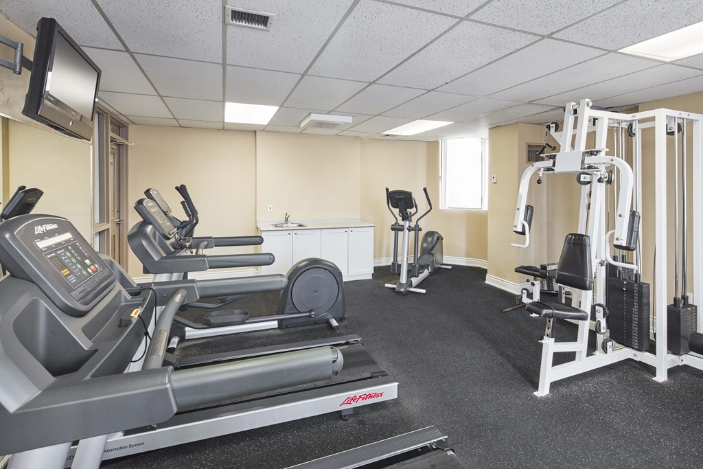 a gym with cardio equipment and weights on the floor