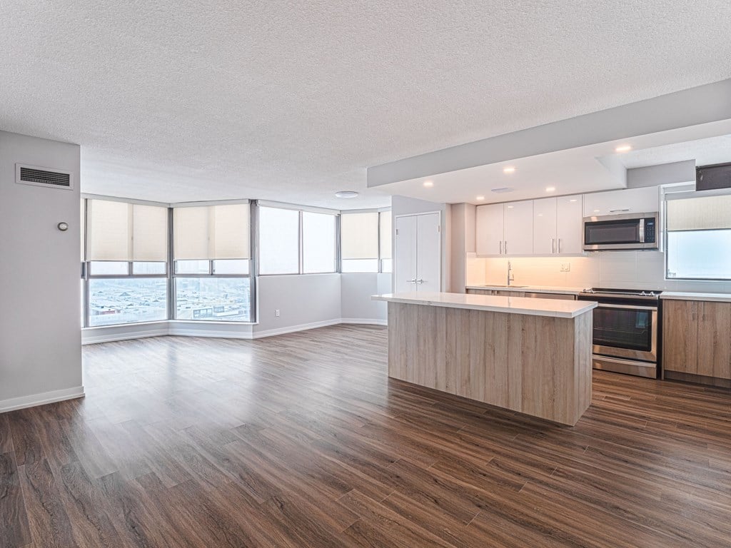 an open kitchen and living room with wood flooring and a large window