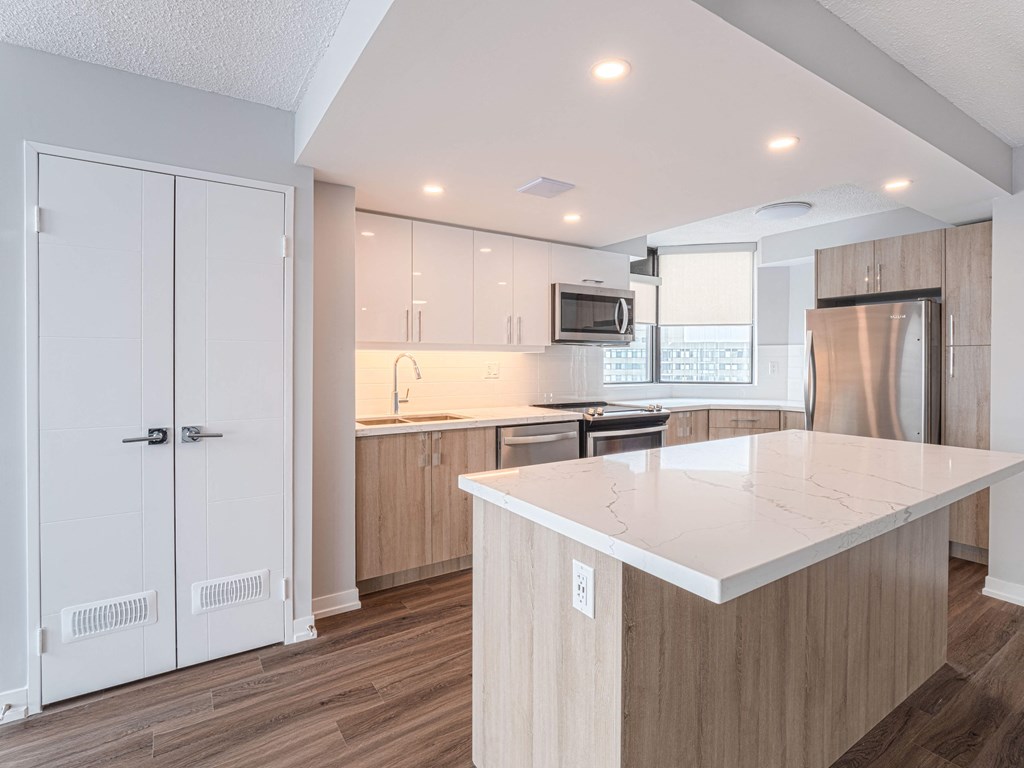 a kitchen with a large island and a stainless steel refrigerator