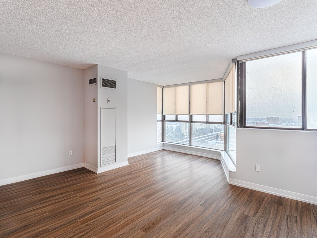 an empty living room with wood flooring and large windows