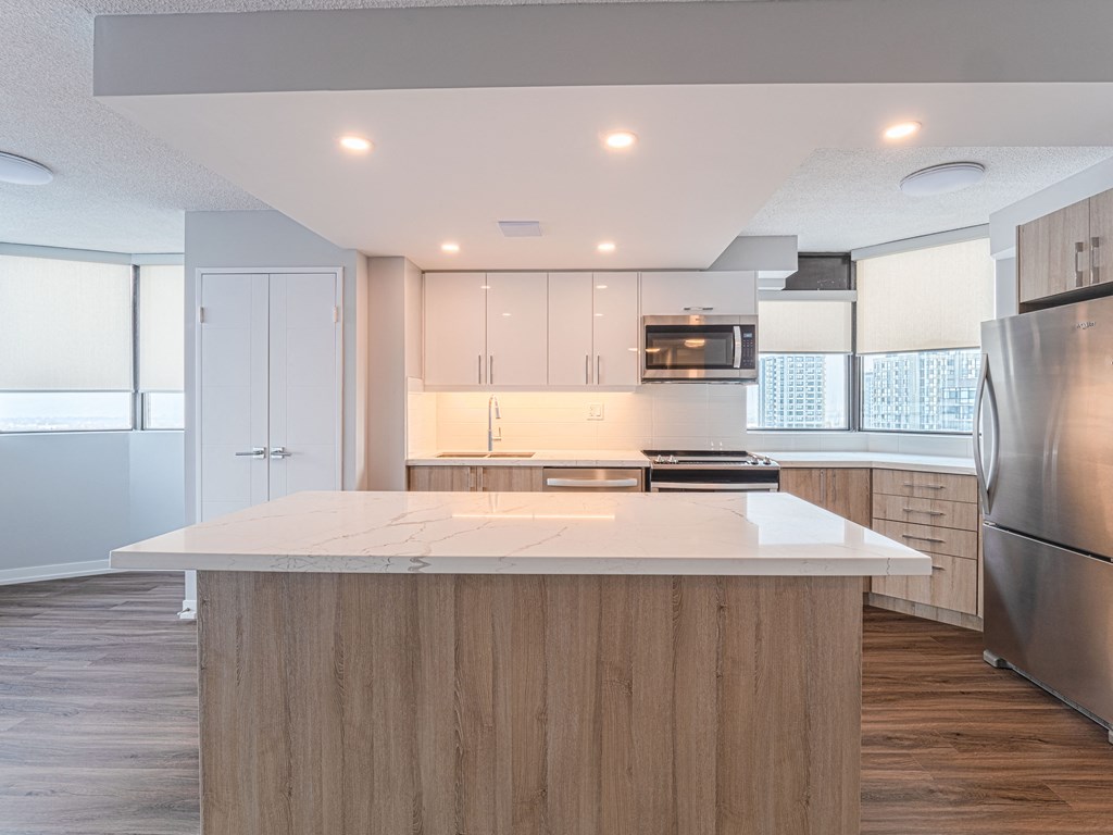 a kitchen with a white counter top and a stainless steel refrigerator