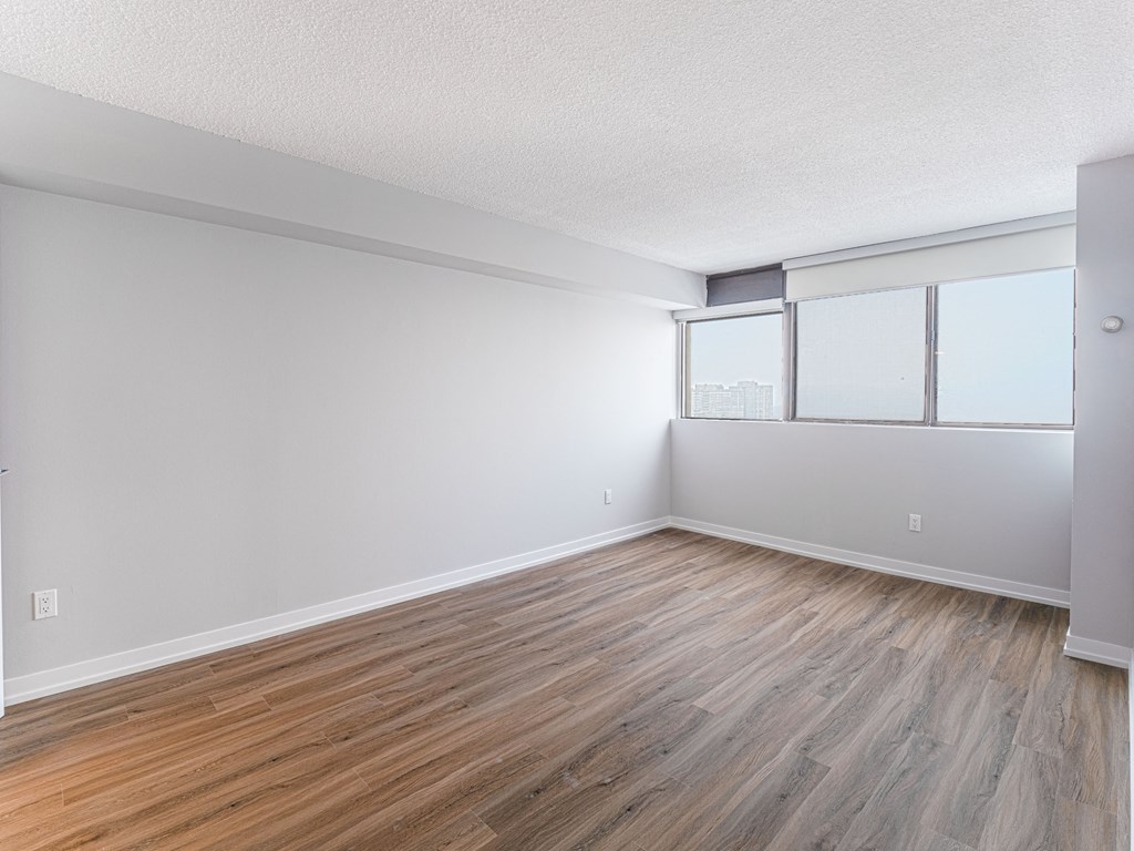 an empty living room with wood flooring and a window