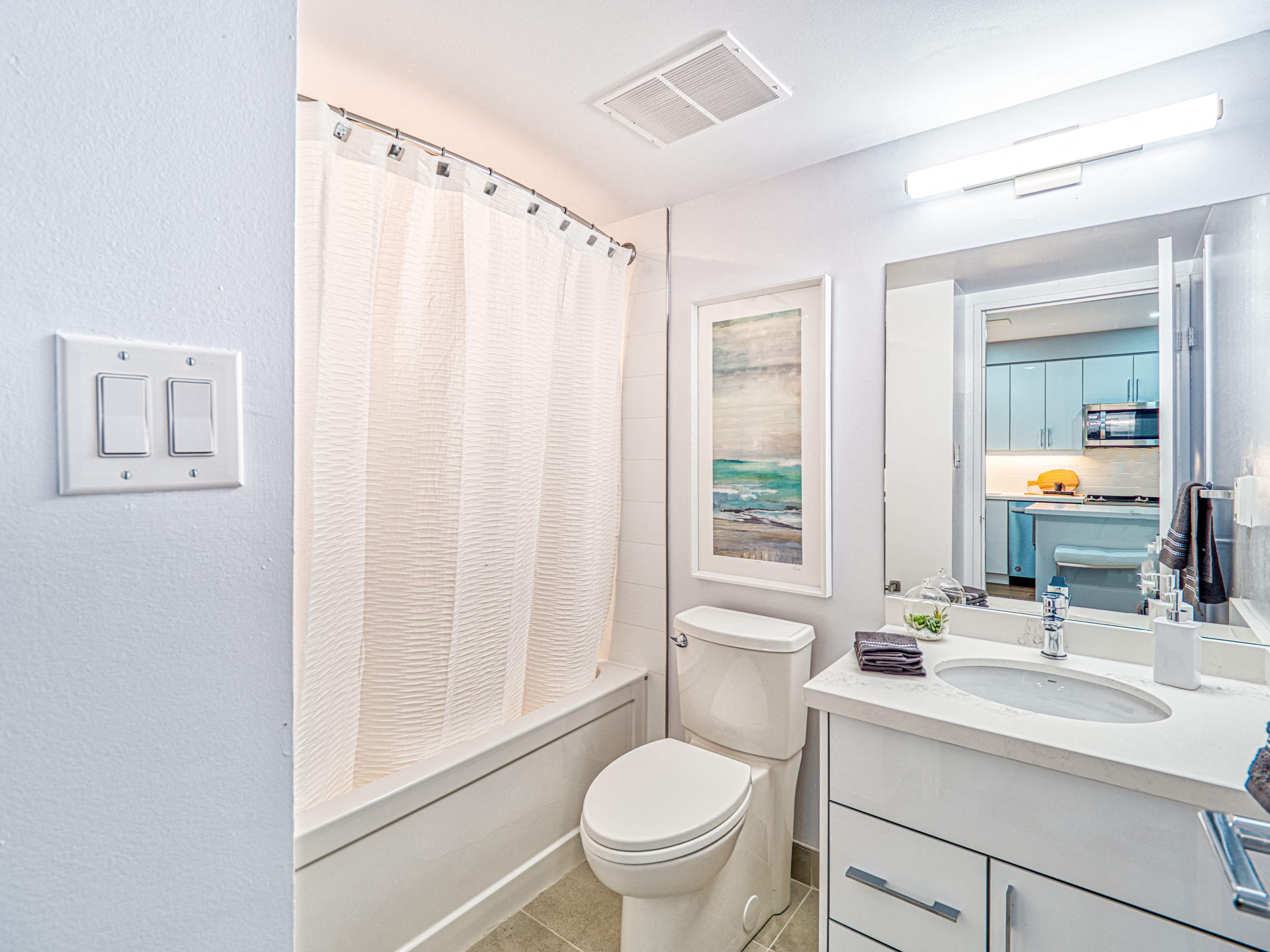 In-suite washroom with shower curtain and wall art