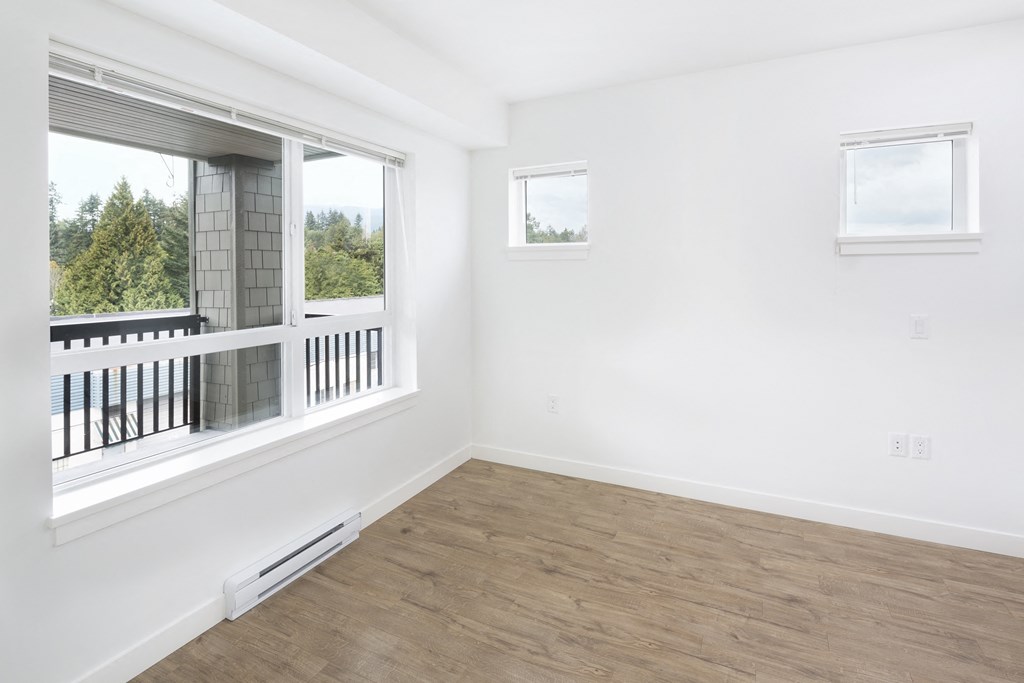 an empty room with a window and a wooden floor