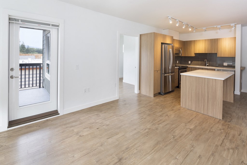 a living room and kitchen with a door to a balcony