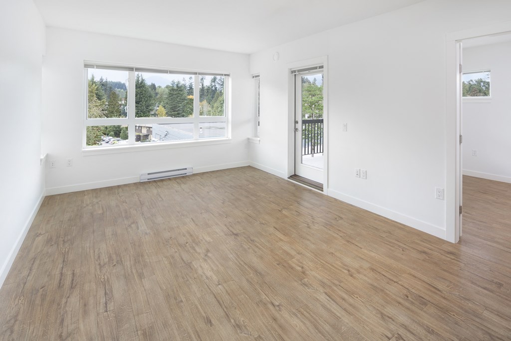 an empty living room with wood flooring and a window