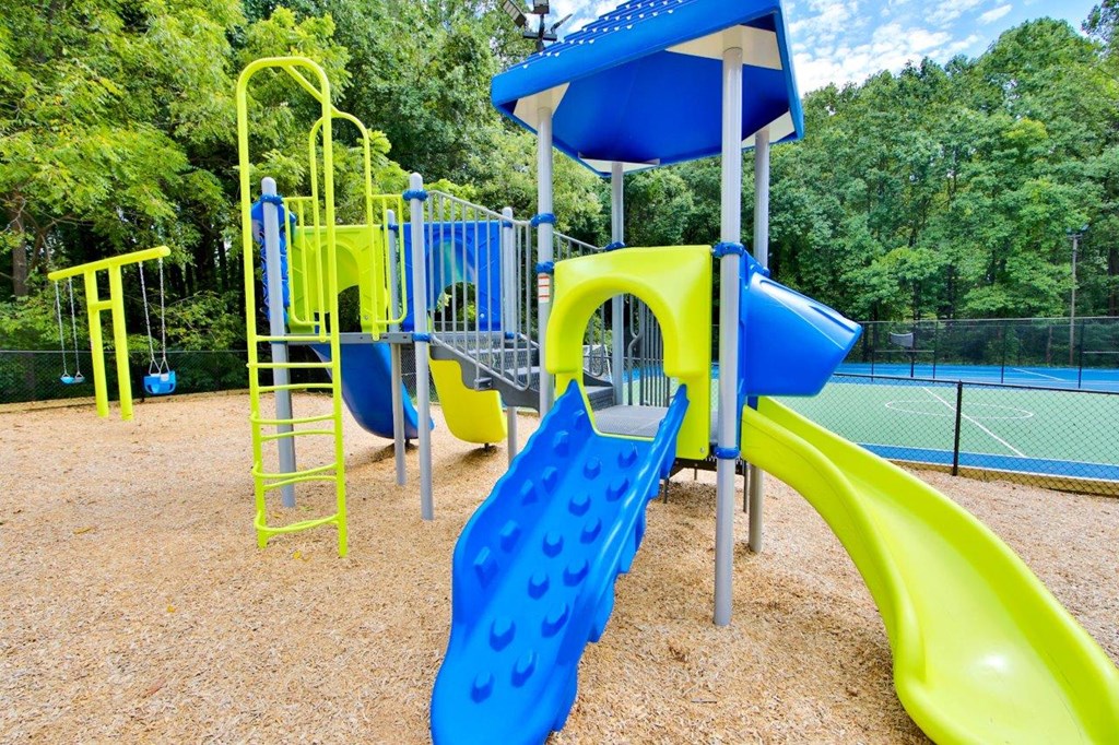a playground with a swing set and slides at a park