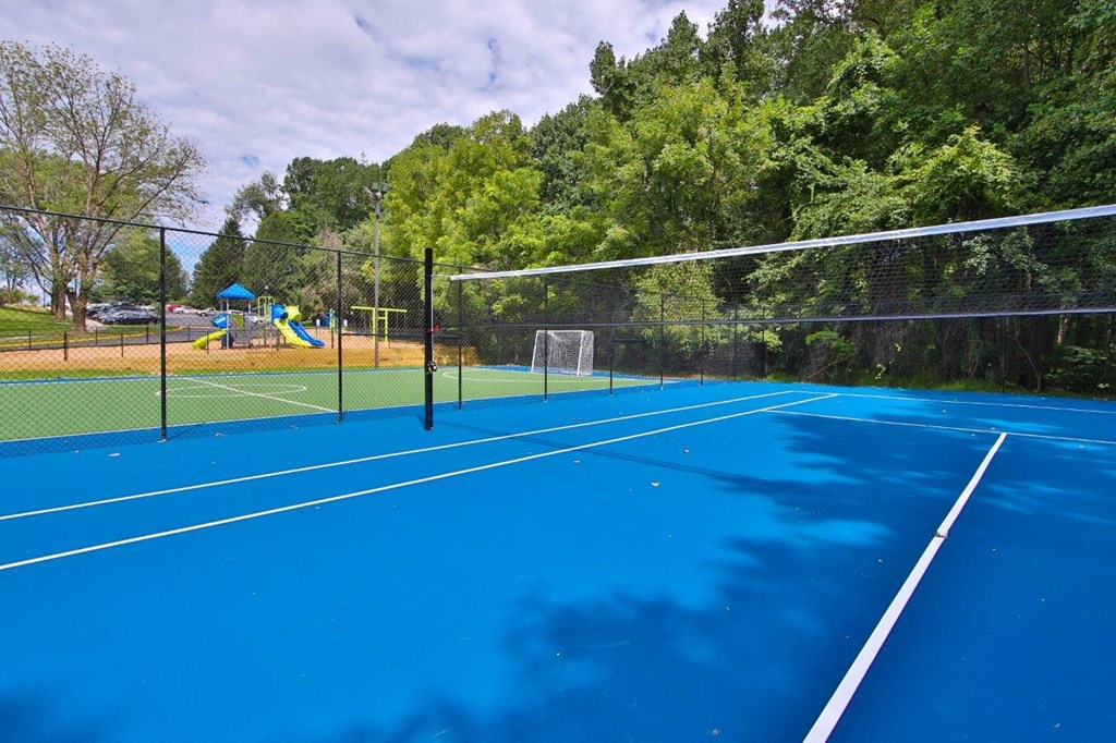 a tennis court with a playground in the background