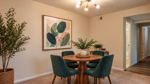 A dining room with a round table and green chairs.