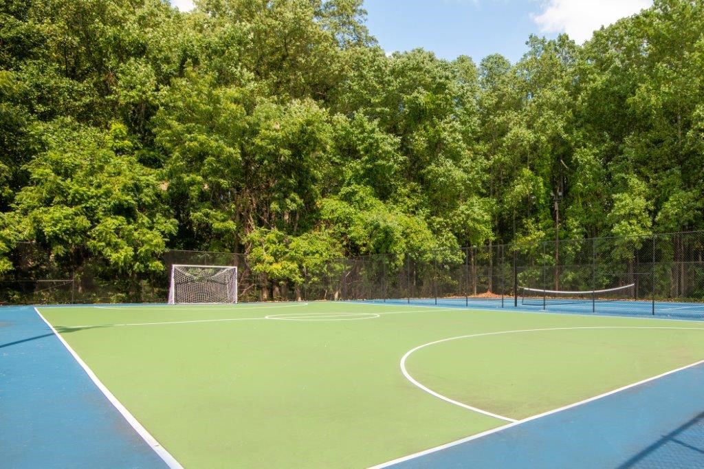 a tennis court with a fence and trees