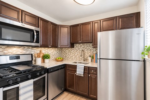 A kitchen with brown cabinets and stainless steel appliances.