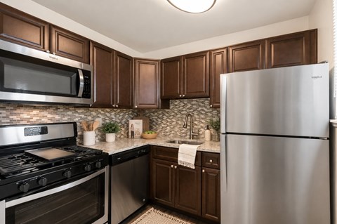 A modern kitchen with dark brown cabinets and stainless steel appliances.