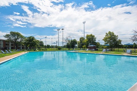a large swimming pool with trees and a cloudy sky