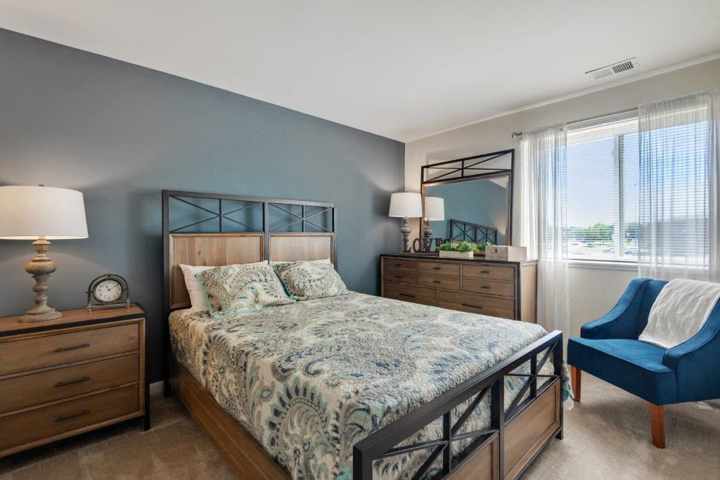 a bedroom with a bed and a chair and a window