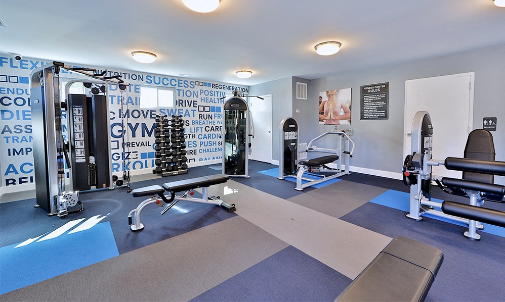 a fitness room with weights and exercise equipment at the enclave at university crossings apartments