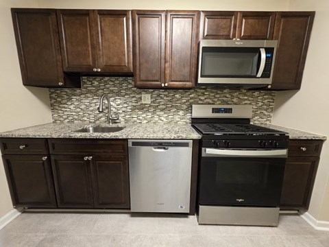 A kitchen with brown cabinets and a granite countertop.