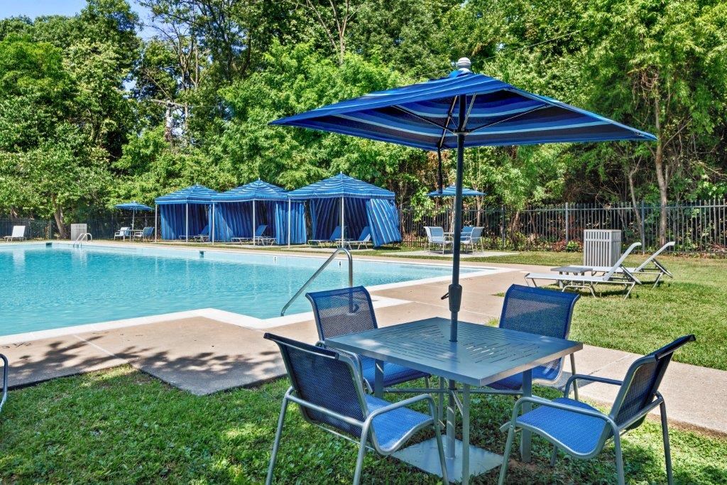 a table with chairs and an umbrella next to a pool