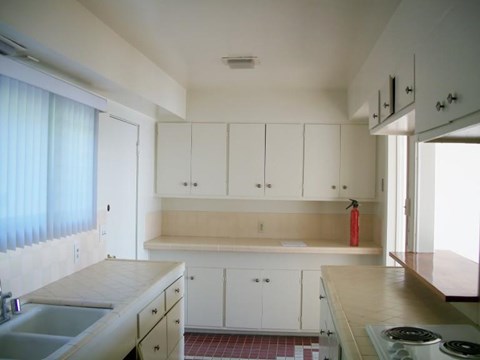 A kitchen with white cabinets and a red fire extinguisher.