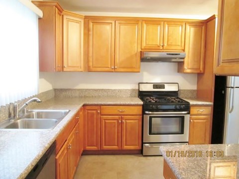 A kitchen with wooden cabinets and a stove top oven.