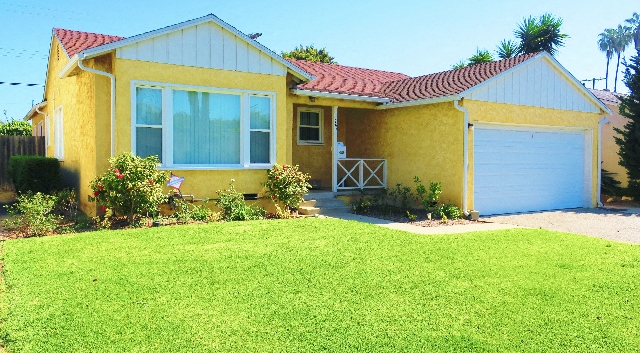 A yellow house with a red roof and a white garage door.