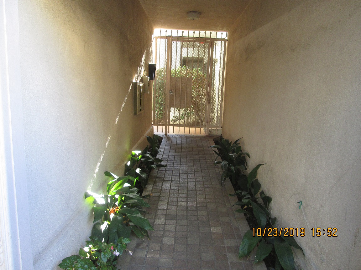 a long hallway with plants and a gate