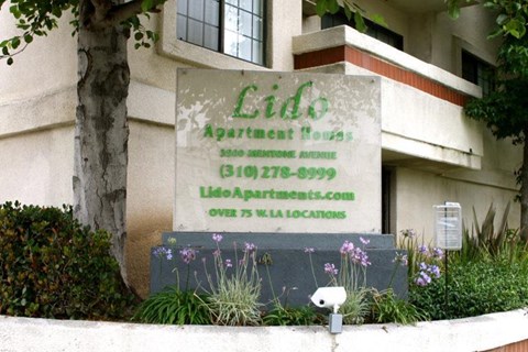 a sign in front of a building with flowers