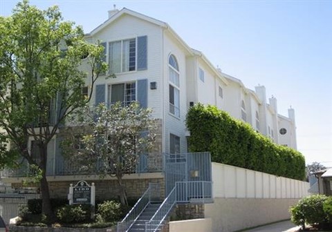 A white building with a green hedge on the side.