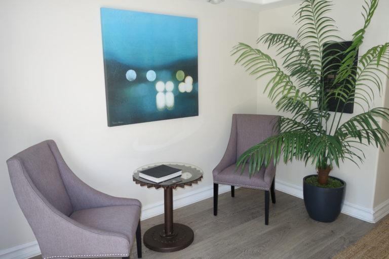 a living room with two chairs and a table and a painting